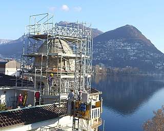 Ouvriers travaillant sur un échafaudage pour rénover une coupole avec vue sur le lac et les montagnes