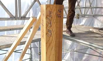 Poutre en bois avec signatures et dates, sur un chantier avec échafaudage et personne