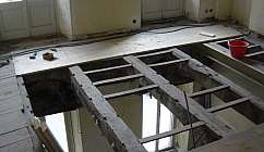 Intérieur d'une pièce en rénovation avec poutres en bois apparentes et panneau de bois appuyé