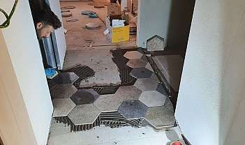 Homme posant des carreaux hexagonaux de différentes couleurs sur un sol en construction