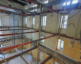 Structure interne d'un bâtiment en rénovation avec des poutres métalliques et des murs partiellement démolis