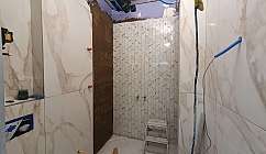 Salle de bain en cours de rénovation avec des carreaux blancs effet marbre et un mur avec des carreaux en chevrons