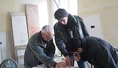 Trois hommes discutent et regardent des documents sur un chantier de construction intérieur