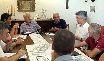 Groupe d'hommes assis autour d'une table avec des projets et des documents lors d'une réunion