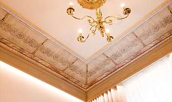 Soffitto con decorazioni floreali e lampadario dorato in una stanza luminosa