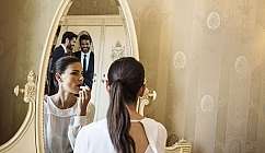 Donna con capelli raccolti si trucca davanti a uno specchio antico in una stanza elegante