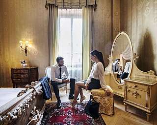Two people sitting in a room decorated with classic furniture.
