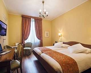 Zimmer mit Doppelbett, Schreibtisch und Fernseher.