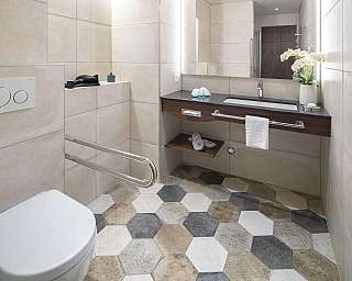Intérieur d'une salle de bain avec lavabo, WC et carreaux hexagonaux décoratifs.