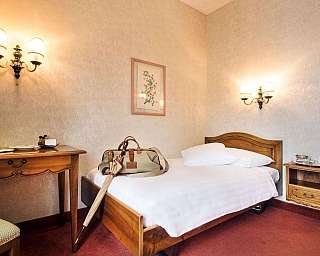 Interno di una camera con letto, scrivania e valigia.