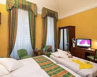 Interno di una camera con letti, armadio e TV.