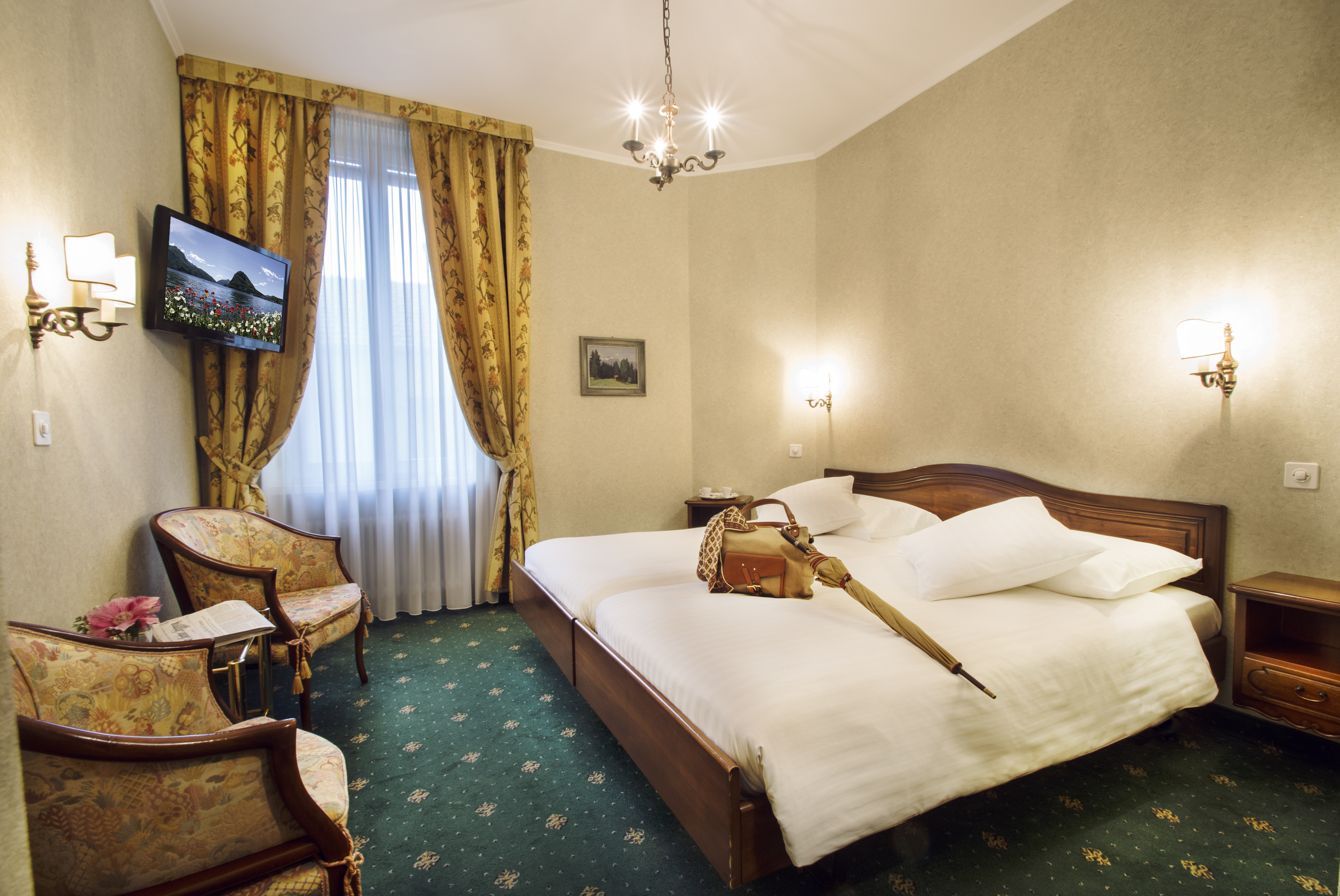 A bag and an umbrella lie on the double bed with white duvet cover