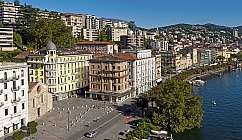 Panorama du bord du lac de Lugano avec des bâtiments et des arbres.