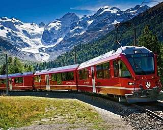 Un treno rosso attraversa un paesaggio montano con ghiacciai.