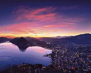 Evening view of Lake Lugano with mountains and a colourful sky.