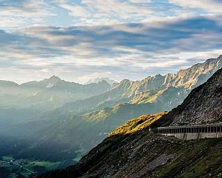 Vue de montagnes avec des nuages et un sentier au premier plan.