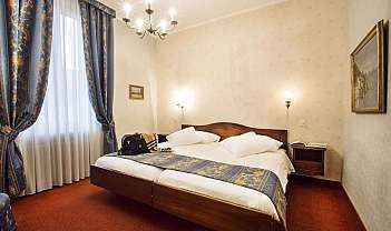 Interno di una camera d'albergo con letto e tende decorative.