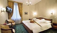 Interno di una camera d'albergo con letti e decorazioni classiche.