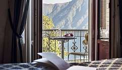 Balcone con vista su montagne e lago, tavolo con frutta.