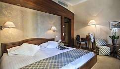 Interno di una camera d'albergo con letto e arredi raffinati.