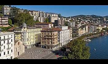 Panorama di edifici lungo un fiume con montagne sullo sfondo.