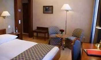 Camera d’albergo con letto, tavolino e poltrone.