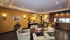 Camera d'albergo con zona soggiorno e cucina attrezzata.