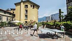 Persone che giocano a scacchi e ping pong in un cortile.