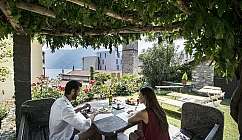 Coppia che pranza in un giardino con vista sul lago.