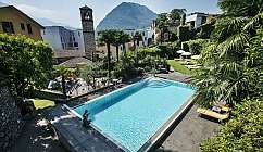 Vista panoramica di una piscina circondata da giardini e montagne.