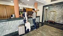 Due persone al banco della reception con valigie.