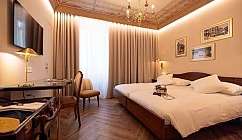 Interno di una camera d'albergo con letti e decorazioni classiche.