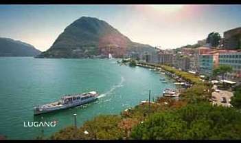 Panorama del lago di Lugano con montagne e barche.