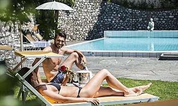 Homme et femme en maillot de bain détendus sur des transats près d'une piscine extérieure