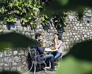 Zwei Personen sitzen an einem Tisch mit Getränken und Obst.