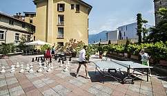 Personnes jouant aux échecs géants et au ping-pong sur une terrasse ensoleillée