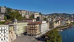 View of the lakeside in Lugano with buildings and trees.