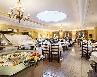 Innenansicht eines Restaurants mit Tischen und Obstbuffet.