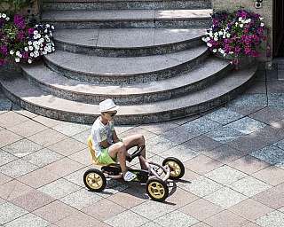 Ein Kind spielt auf einem Go-Kart in einem gepflasterten Bereich.
