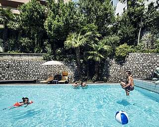 Kinder, die mit einem Ball und einem Schwimmring im Pool spielen.