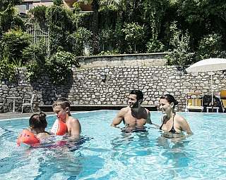 Deux enfants et deux adultes s'amusent dans la piscine.