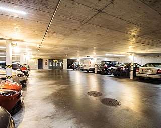 Interior of an underground car park with various cars and lighting.