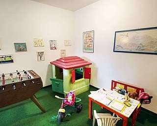 Innenansicht eines Spielzimmers mit Spielzeug und aufgehängten Zeichnungen.