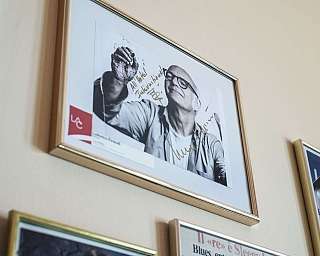 Un portrait encadré d'un homme souriant avec une main levée.