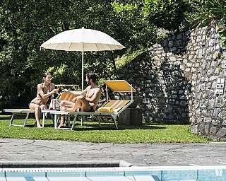 Un couple profitant de boissons sur des chaises longues au bord de la piscine.