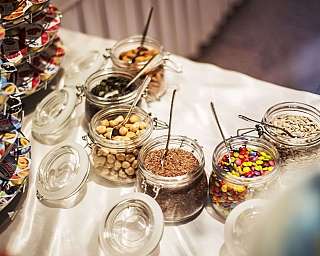 Verschiedene Snacks in Glasbehältern mit Löffeln.