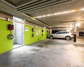 Inside a parking lot with cars and electric charging stations.