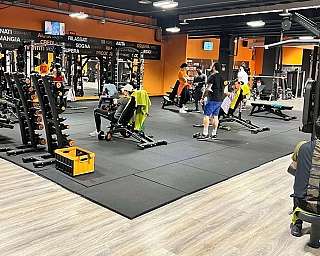 Interno di palestra con persone che si allenano su attrezzi e pesi