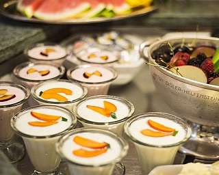 Verschiedene Desserts in Gläsern mit frischen Früchten.