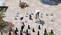 Deux personnes jouent aux échecs avec des pièces géantes sur un échiquier extérieur en pierre